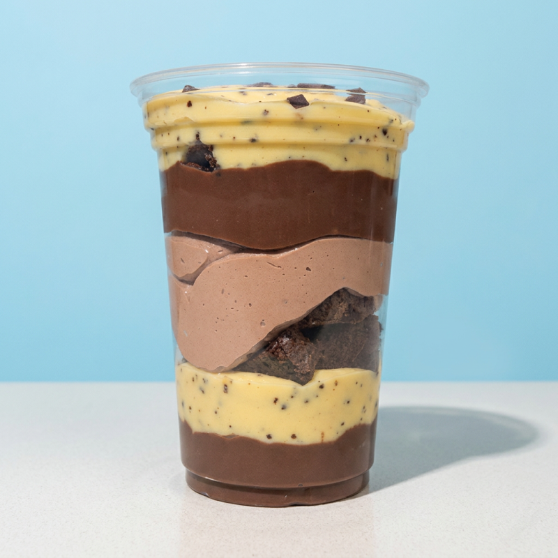 Sobremesa deliciosa montada no copo, composta de camadas brigadeiro cremoso de chocolate ao leite e brigadeiro de maracujá, lasquinhas de brownie e mousse de chocolate para finalizar