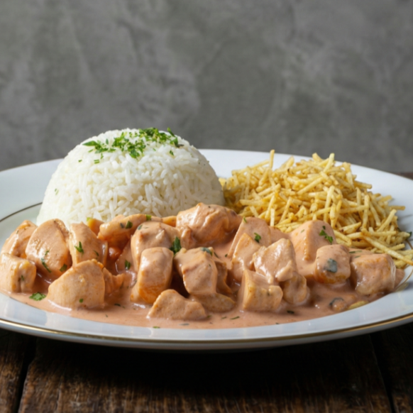 Cubos de frango macios no molho cremoso e bem temperado, servidos com arroz soltinho e batata palha crocante. Clássico irresistível.