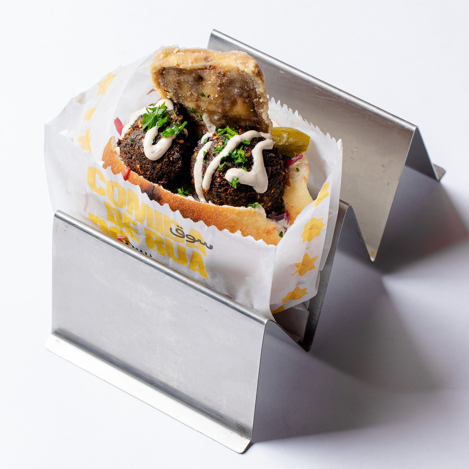 SANDUÍCHE DE ORIGEM EGÍPCIA COM FALAFEL, HOMUS, SALADA, RELISH DE REPOLHO ROXO, PICLES, BERINJELA EMPANADA E MOLHO TAHINE. VEGANO. CONTÉM GLÚTEN. CONTÉM OLEAGINOSAS.