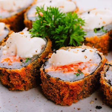Delicioso enrolado de arroz com muito salmão e cream cheese, empanado na farinha, depois de frito cortado em 8 unidades e finalizado com molho tare artesanal