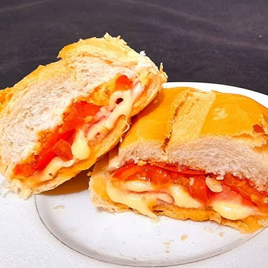 Sanduíche no pão francês com presunto, queijo, tomate e orégano derretido na chapa à moda paulistana, uma opção saborosa e rápida.