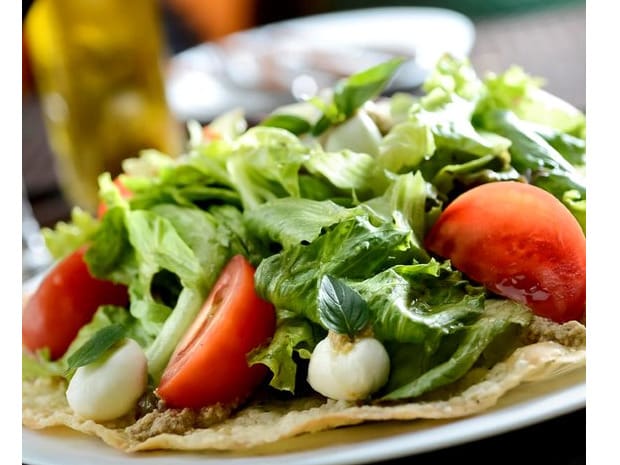 Alface americana, rúcula, muçarela de búfala, tomate, manjericão, azeitonas pretas, torradas e molho pesto.