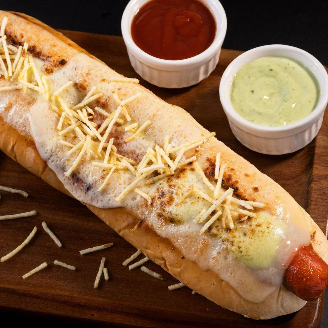 PÃO DE BATATA DE 25CM APROXIMADAMENTE, 2 SALSICHAS, KETCHUP,MOLHOS, QUEIJO RALADO, BATATA PALHA, QUEIJO MUSSARELA MAÇARICADO.