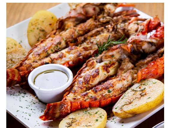 Duas lagostas inteiras grelhadas. Acompanha risoto de limão siciliano, batata ao forno e manteiga de ervas especiais.