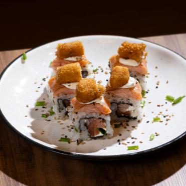Arroz e gergelim por fora, recheado com salmão fresco cream cheese e cebolinha por dentro + uma camada de salmão por cima maçaricado com pedaços de camarão frito. *Não acompanha Molhos nem Hashi* (Valor de 5 unidades).
