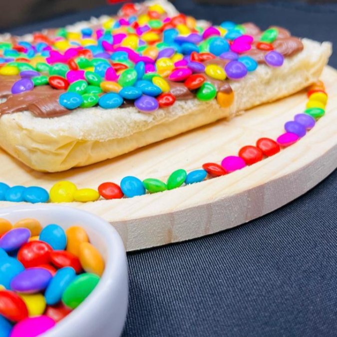 Pão de hot dog, mussarela, chocolate ao leite e confeti.