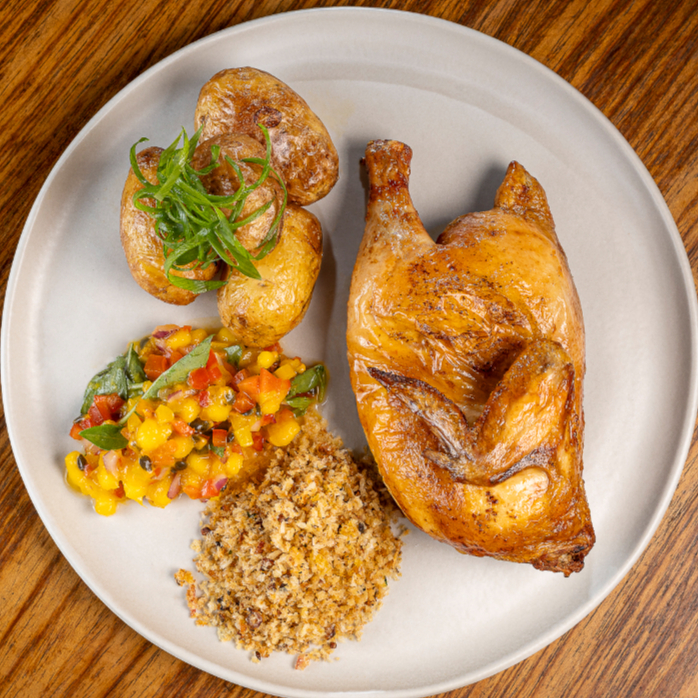 Meio galeto marinado no cítrico de laranja e ervas, assado lentamente. Servido com batatas calabresa douradas, farofa crocante de maracujá, vinagrete de manga, pimenta vermelha e manjericão