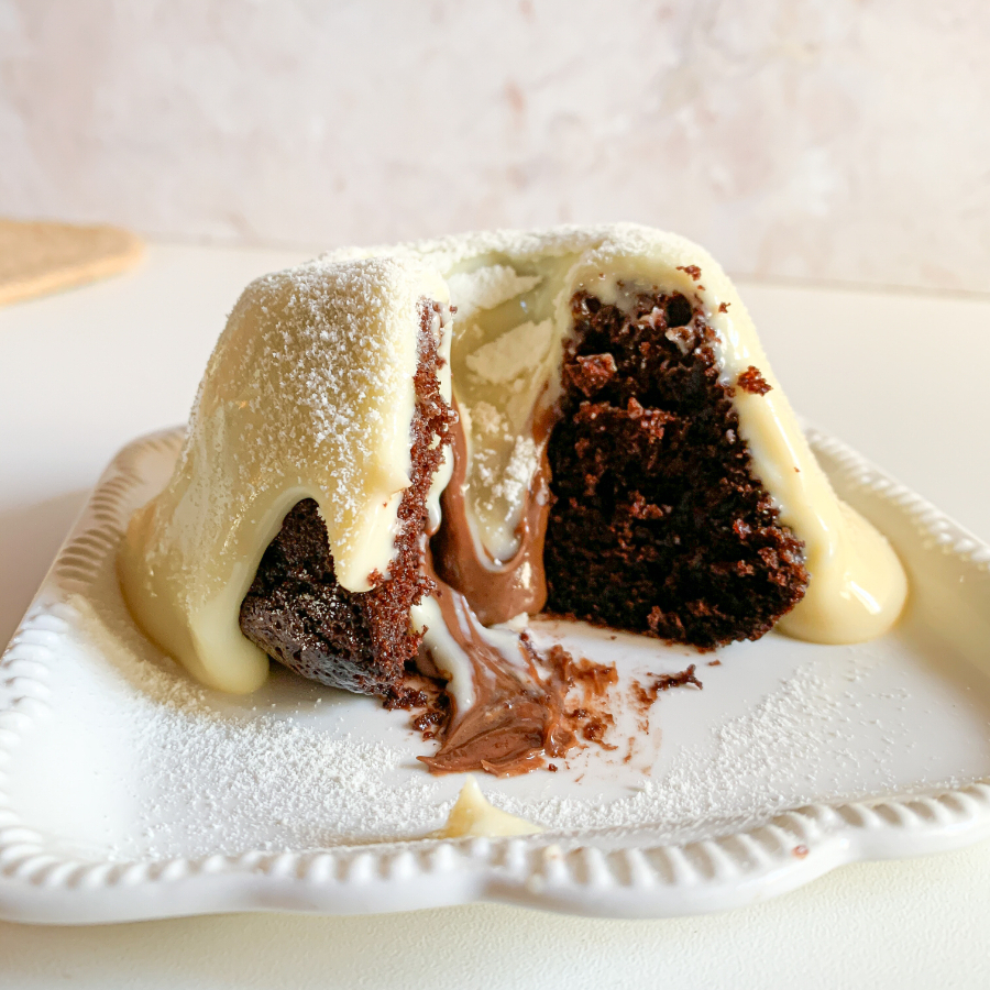 Bolinho caseiro de chocolate recheado com nutella no meio, coberto com calda de ninho cremoso. Aprox. 190g