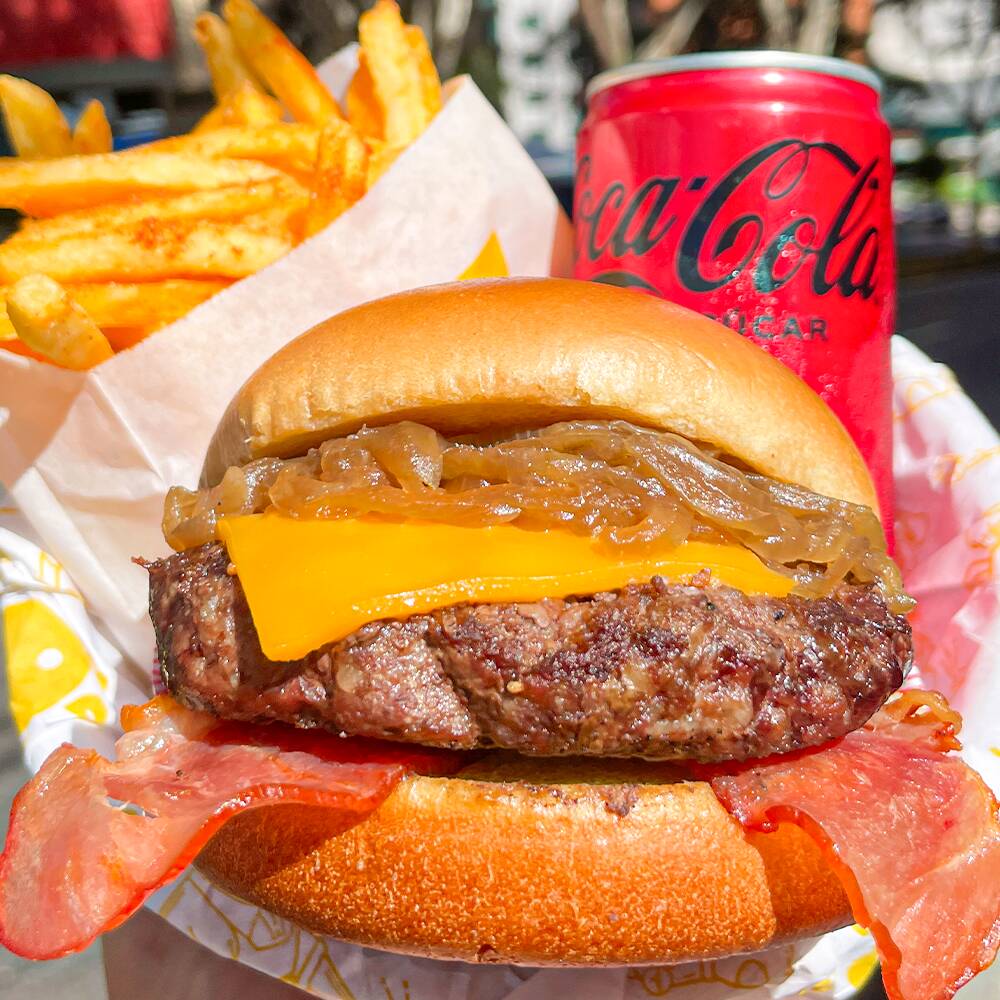 O combo mais pedido: Niquito's Burguer Artesanal 100% Carne(150g) com queijo cheddar fatiado derretido, bacon douradinho e o famoso molho Nico's + batatinha frita crocante com tempero especial + Coca-Cola lata 220ml gelada. Hamburguer com combinação perfeita, preço justo.