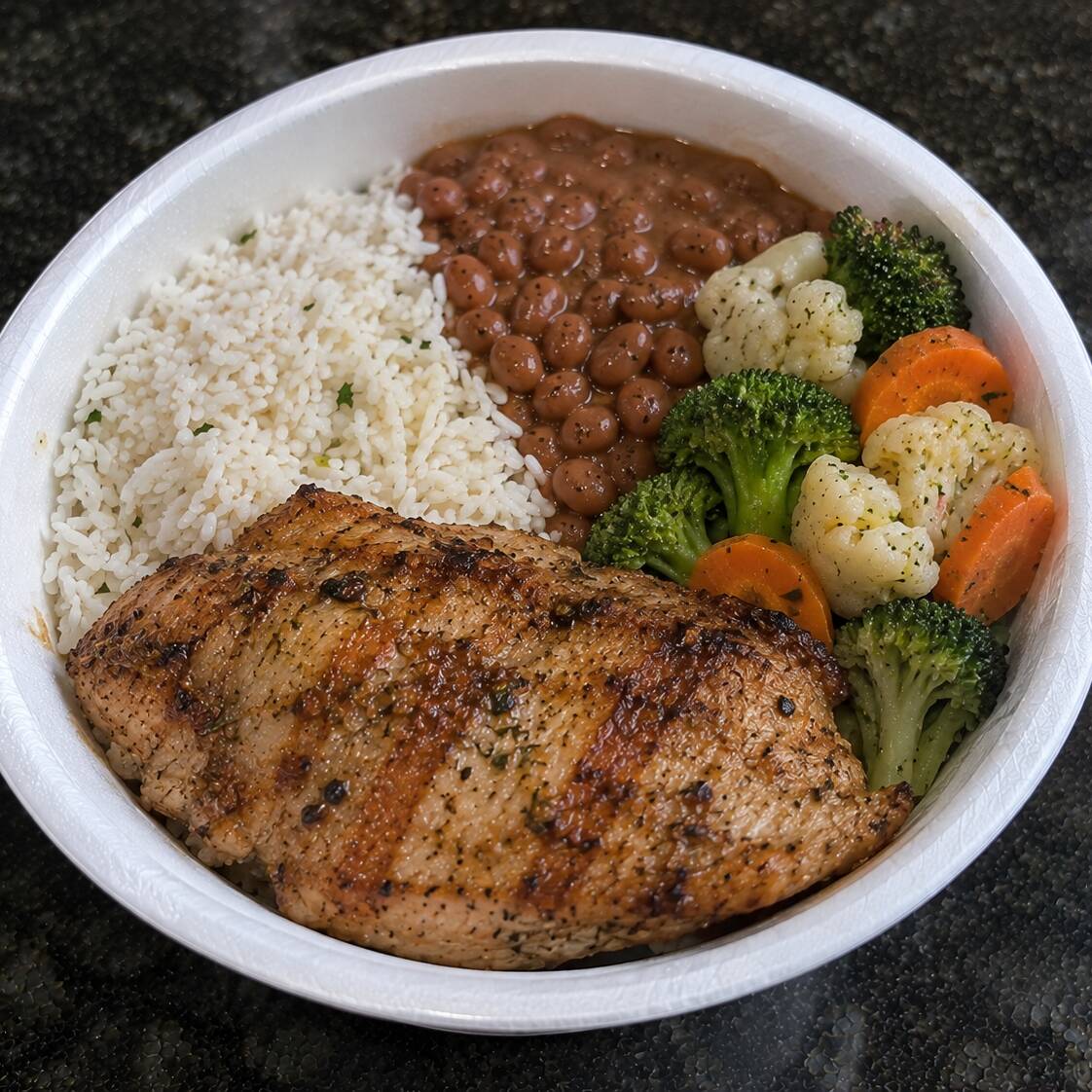 Delicioso almoço com arroz, feijão, legumes à vapor e um filé de frango grelhado na brasa, temperado com nosso mix de temperos.
