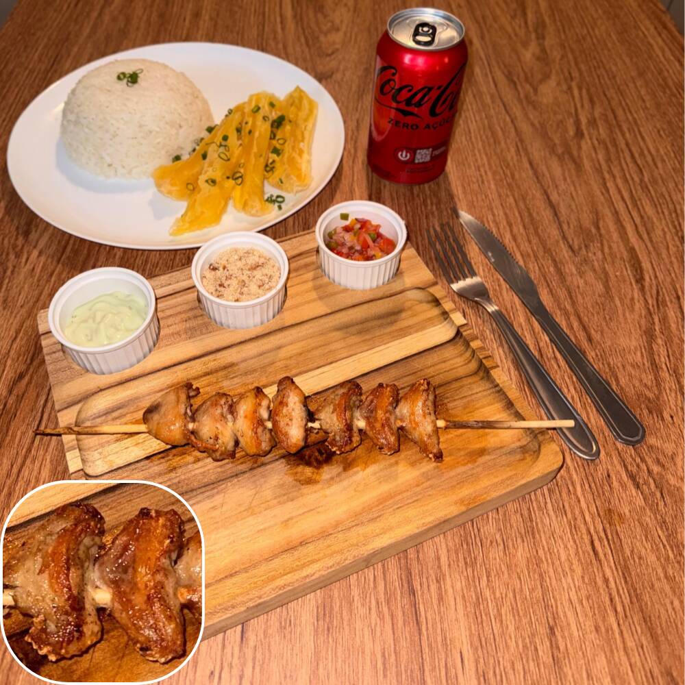 Espeto de sambiquira acompanhado por arroz, mandioca, vinagrete, farofa crocante e molho verde.