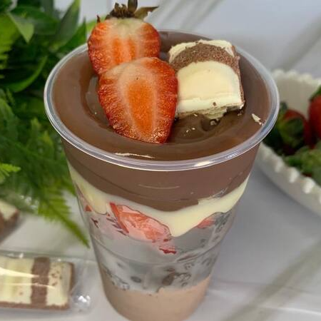 Feito com mousse de chocolate, pedaços de Brownie, morangos frescos e brigadeiro de chocolate. Finalizado com morango e um Kinder Bueno.