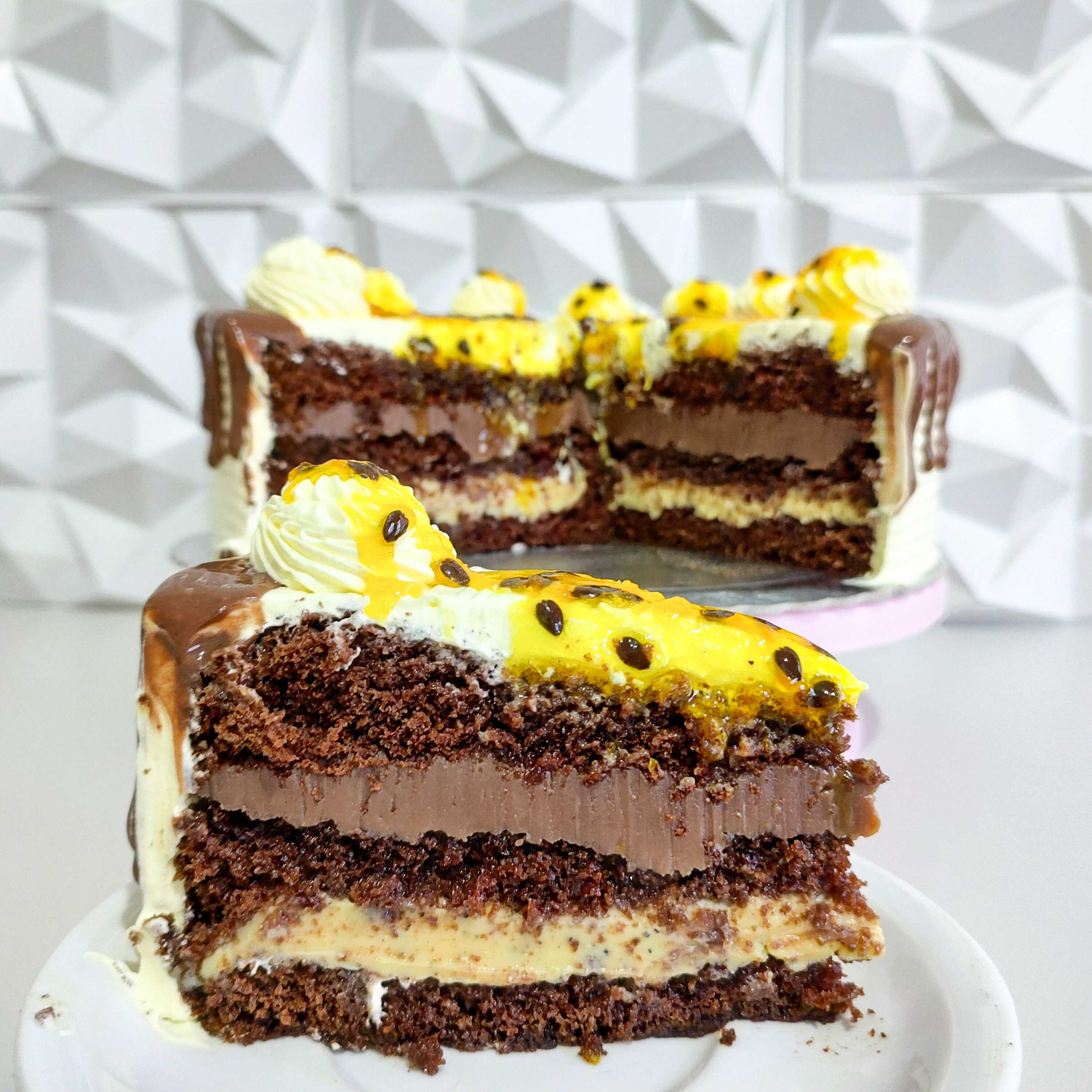 Fatia de Torta Maracujá com Brigadeiro: massa de chocolate fofinha, camada cremosa de brigadeiro e recheio de maracujá que traz o equilíbrio perfeito entre doce e azedinho. Uma fatia intensa, geladinha e impossível de resistir.