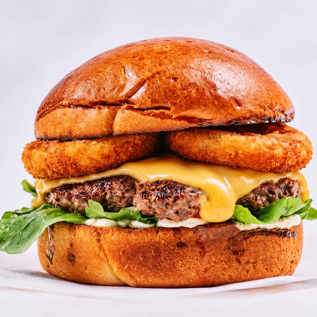 Hambúrguer Artesanal de 160gr, cheddar cremoso, onion rings, molho barbecue, rúcula, maionese da casa, pão brioche.