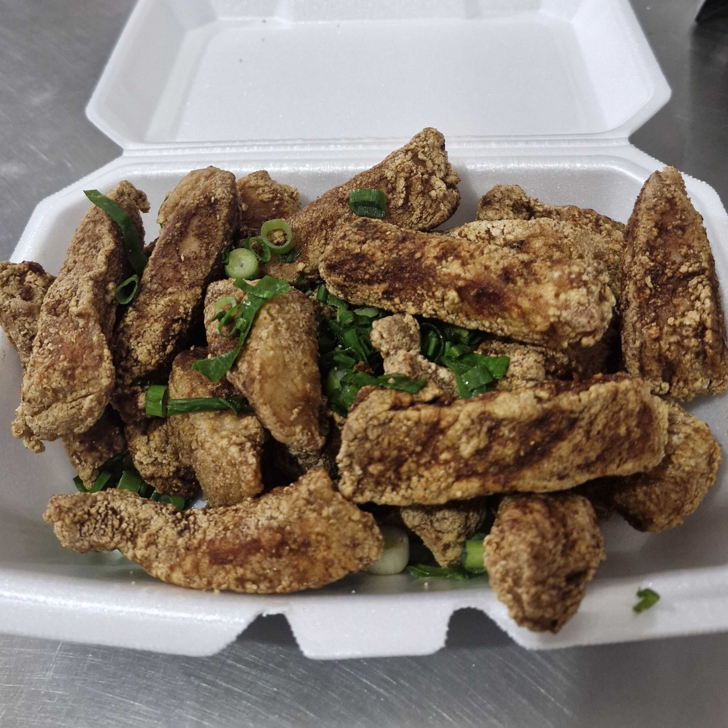 pedaços de lombo suíno em forma costelinha frito, salpicado com cebolinha.