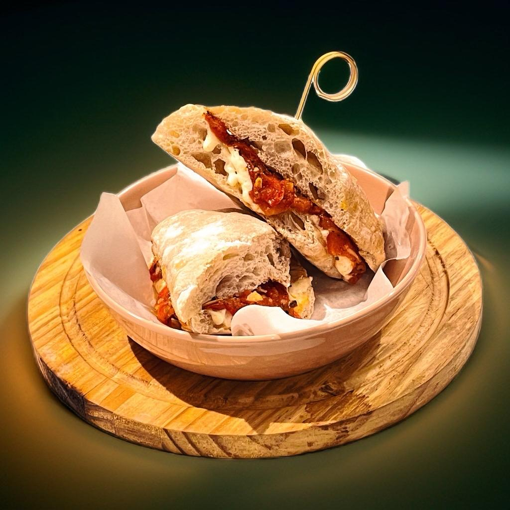 Pão ciabatta de fermentação natural, recheado com creme de três queijos e tomate confitado. Vegetariano.