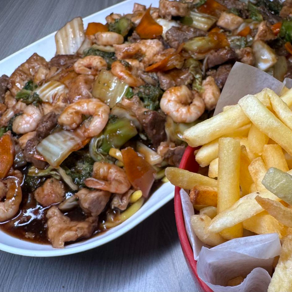 Macarrão caseiro com carne, frango, camarão e legumes ao molho shoyu especial da casa. Os legumes são: brócolis, acelga e cenoura. Ganhe Batata frita.