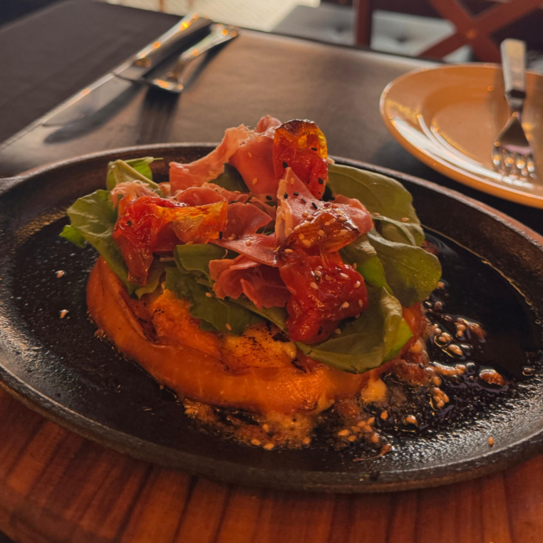 Sabor, textura e tradição em um só prato. Nosso Provolone curado é selado até ficar crocante por fora e super derretido. Servido coberto com a combinação que amamos: Presunto Parma salgadinho, Tomate maduro e Rúcula fresca para dar o contraste ideal. A entrada que não pode faltar na sua mesa.