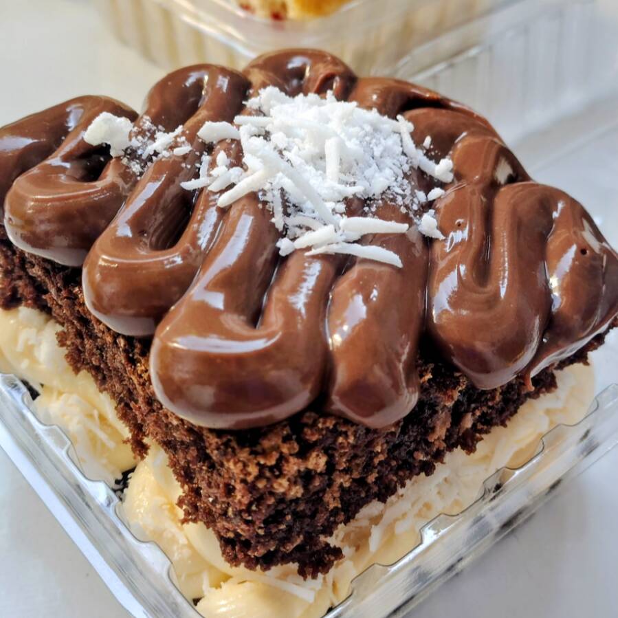 bolo de corte com camadas de massa preta fofinha e molhadinha e recheio cremoso de ninho com coco e chocolate.
