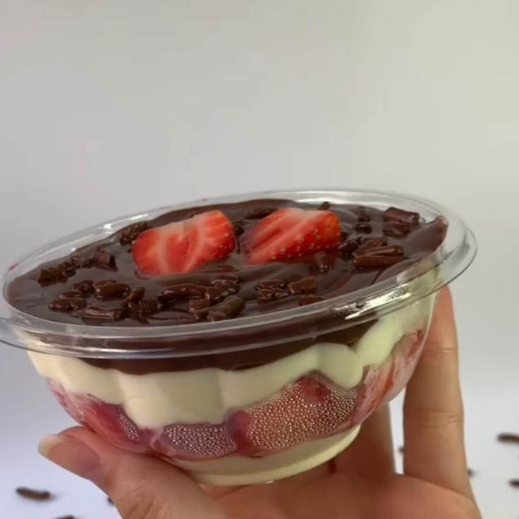 Bombom aberto, morango, creme de Ninho e ganache de chocolate. A cremosidade do bombom tradicional, servido em pote individual para você saborear sem culpa e com muito prazer.