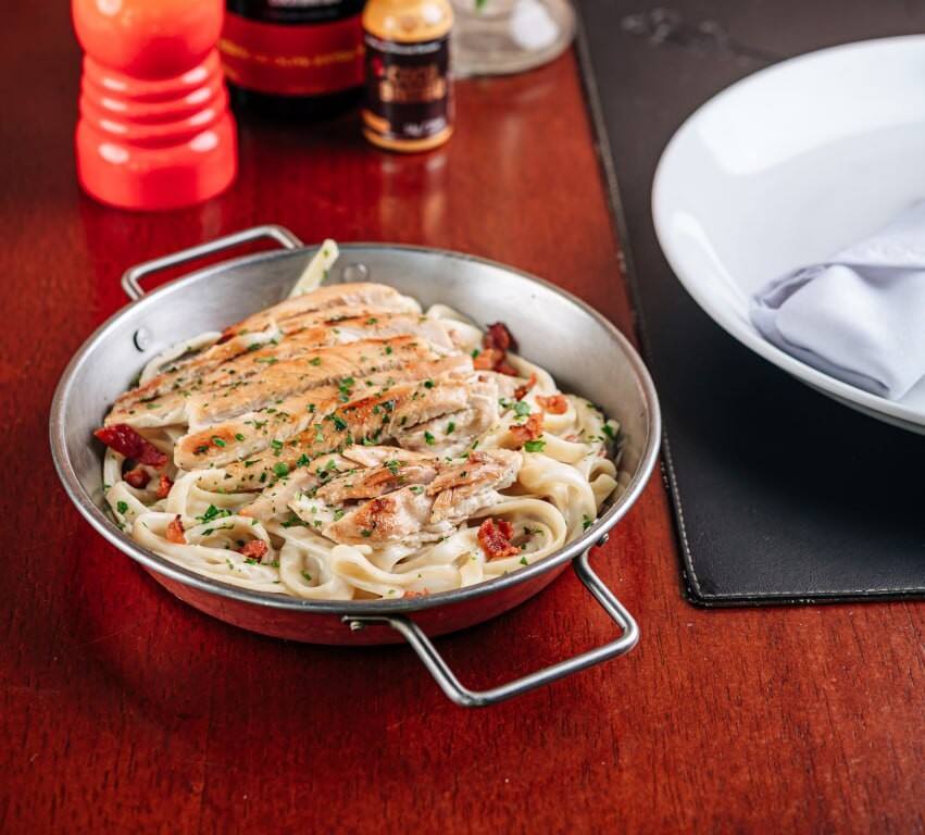 Filé de peito de frango grelhado sobre fettuccine com molho alfredo e bacon.