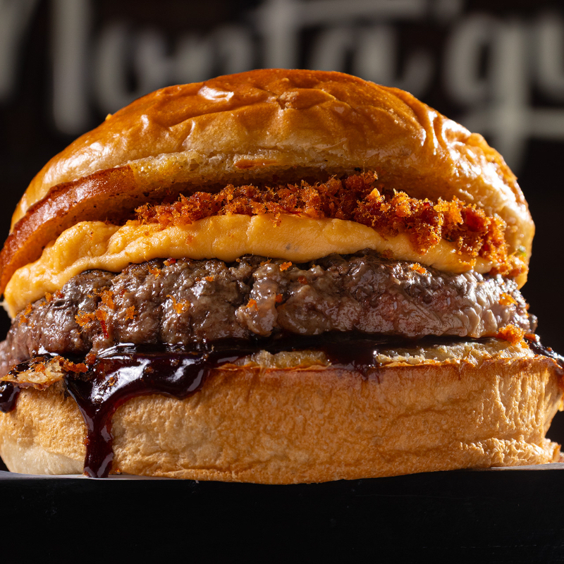 Pão de batata, blend da casa (90g), queijo cheddar da casa, molho barbecue, farofa de bacon, onion ring.