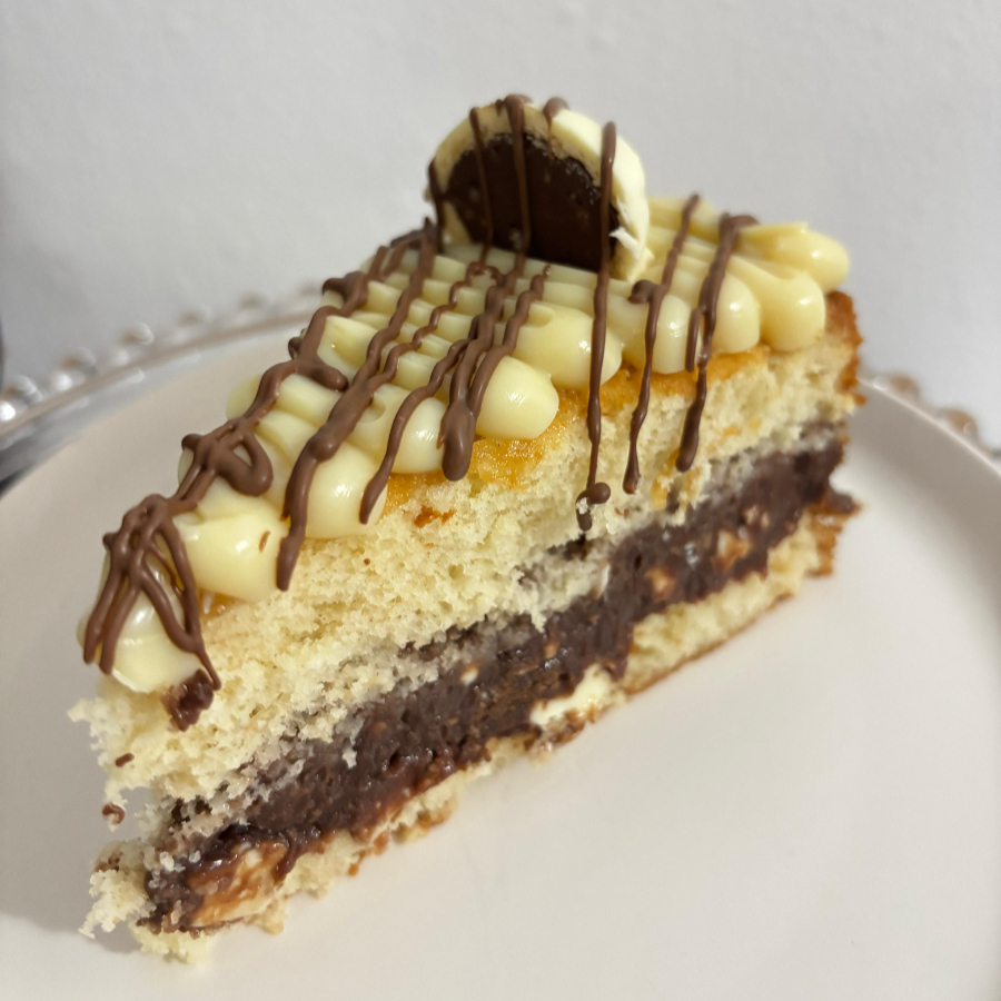Massa branca fofinha e molhadinha, com recheio de.creme de chocolate e ouro branco picados, finalizado com um creme de ninho