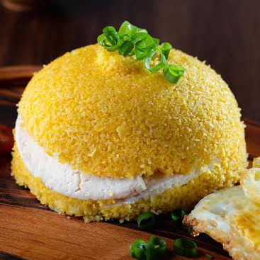 Cuscuz, recheado com queijo mussarela por dentro e com uma cobertura de uma fatia de queijo