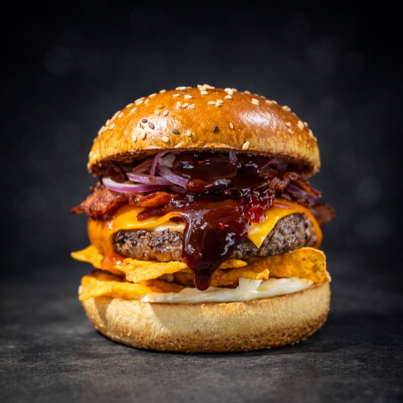 Pão de brioche, com uma camada generosa de Doritos crocante, maionese Hellmann's e o molho Tasty Kones, um hambúrguer artesanal de 120g, fatia de queijo cheddar,tiras de bacon, rodelas de cebola roxa, além de uma geléia de pimenta leve e agridoce e o molho barbecue. E o melhor: se você não curtir a pimentinha, é só pedir sem, mas vai perder um sabor especial!