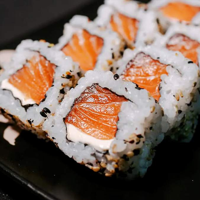 Porção com 10 undiades de uramaki de salmao (arroz enrolado por fora ) com recheio de salmao com cream cheese.