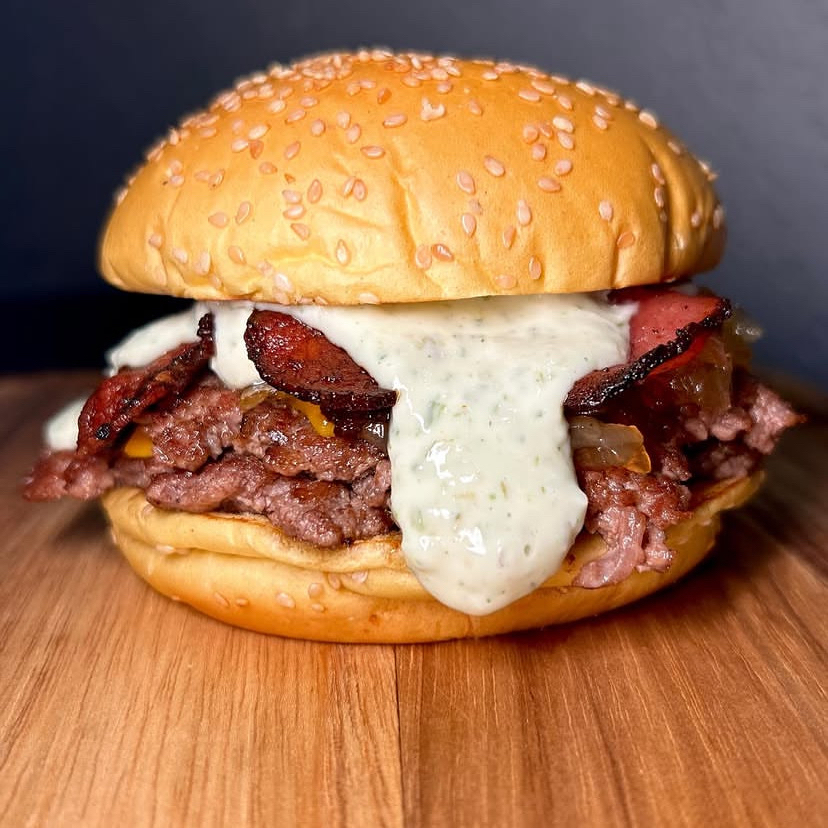 Aprecie o artesanal xpicanha', um prato que exala autenticidade e sabor. Recheado com 180g de uma carne selecionada e especialmente preparada para churrasco, é coberto por uma generosa camada de queijo cheddar derretido. O frescor das verduras se alia perfeitamente ao bacon, meticulosamente cortado em cubos e frito até a crocância perfeita. A finalização fica por conta do nosso exclusivo molho da casa, que adiciona um toque único e irresistível. Uma verdadeira obra de arte da culinária, feita especialmente para você.