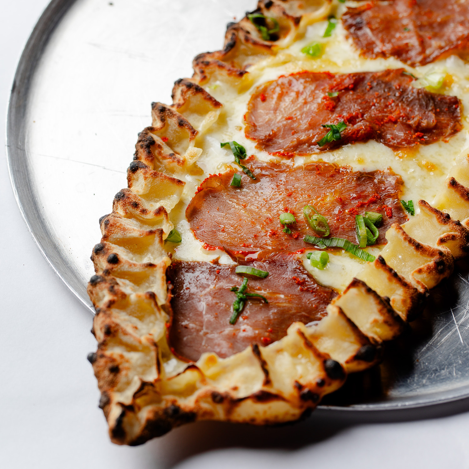 ESFIHA TURCA EM FORMATO DE BARCA DE MUSSARELA, BASTERMÁ (CARNE BOVINA CURADA E CONDIMENTADA, TÍPICA DA ARMÊNIA) E CEBOLINHA. CONTÉM GLÚTEN. CONTÉM LACTOSE.