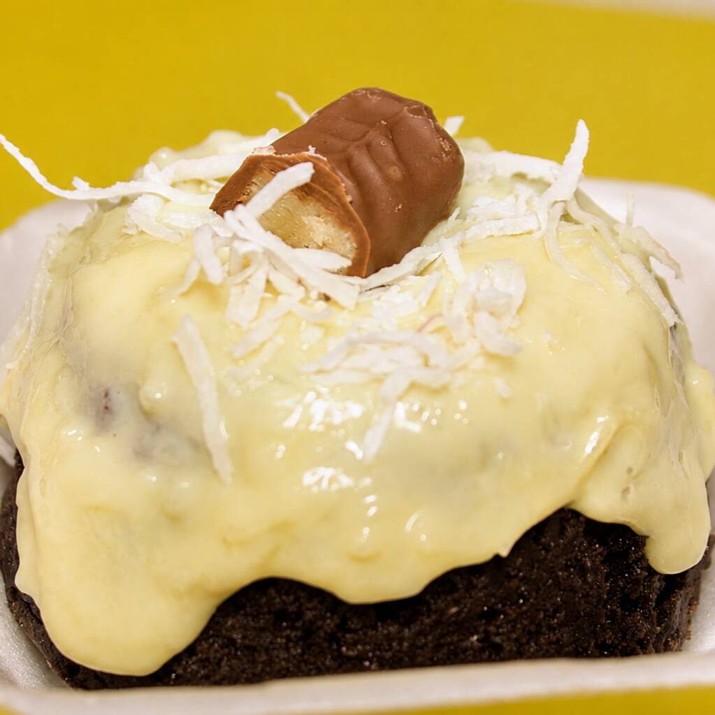 Massa de chocolate macia e fofinha, coberta com brigadeiro cremoso de coco, finalizada com lascas de coco e um delicioso chocolate Prestígio. Receba seu bolo quentinho e aproveite cada pedaço!