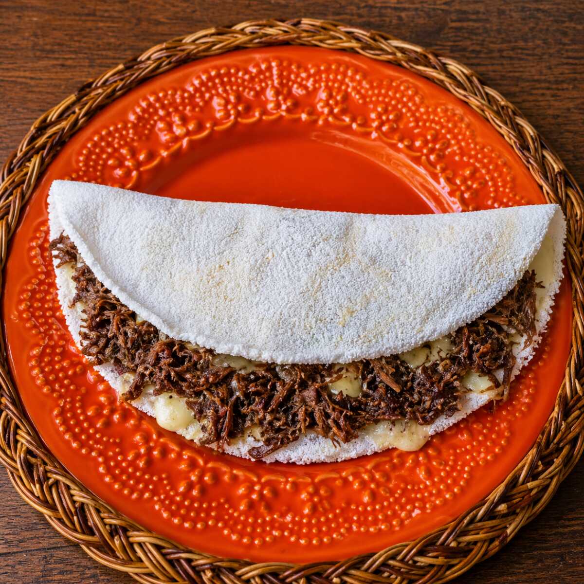 Preparada na hora, esta deliciosa tapioca é recheada com carne de sol desfiada, queijo mussarela derretido e tomate fresco. Uma combinação clássica, suculenta e cheia de sabor, perfeita para quem aprecia o autêntico sabor da carne de sol.