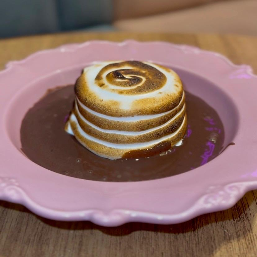 Bolinho de chocolate de casquinha macia e centro recheado, coberto com marshmallow levemente maçaricado e finalizado na hora com uma generosa calda de chocolate quente. Uma sobremesa feita para derreter na primeira colherada.