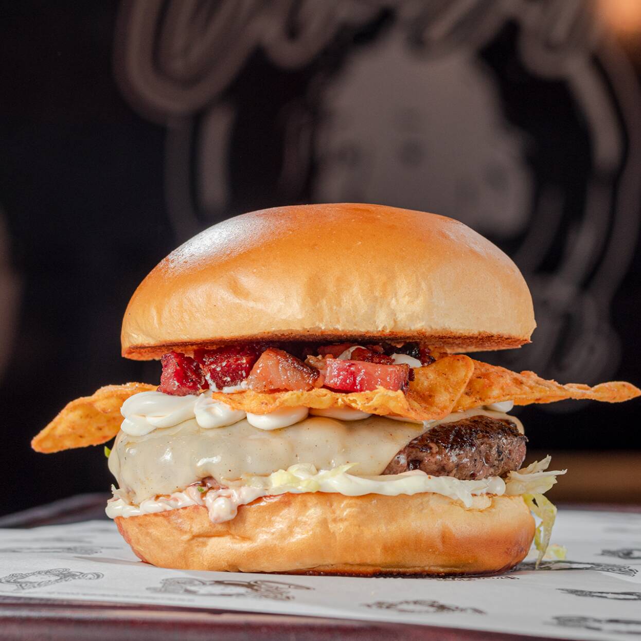 Pão brioche com hambúrguer artesanal de 150g, queijo muçarela derretido, e cream cheese com bacon crocante em cubos. Finalizado com Doritos inteiros para uma crocância surpreendente e maionese especial da casa. Uma explosão de sabores única para quem busca algo diferente!
