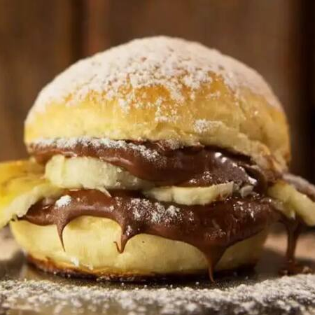 Pão brioche macio recheado com Nutella cremosa e fatias de banana fresca. Uma combinação irresistível de sabores que une o doce da banana com o toque suave de chocolate!