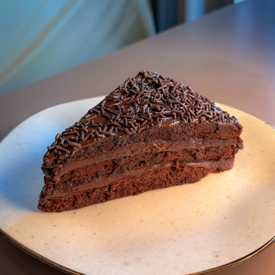 Fatia generosa de Chocolate com brigadeiro meio amargo, feito com cacau puro e granulados de chocolate nobre. Bolo macio, molhado e beeem chocolatudo. (igual a imagem) 250g aproximadamente