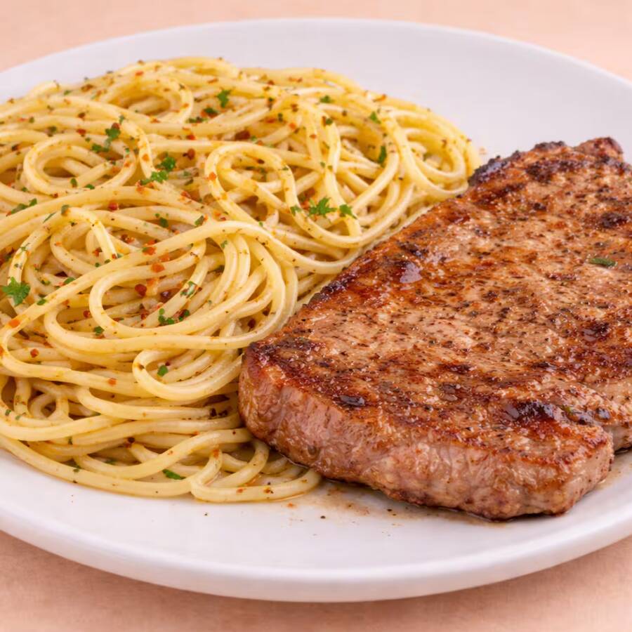Delicioso Macarrão Alho E Óleo Acompanhado Por Um Bife De Pernil Macio E Bem Temperado.