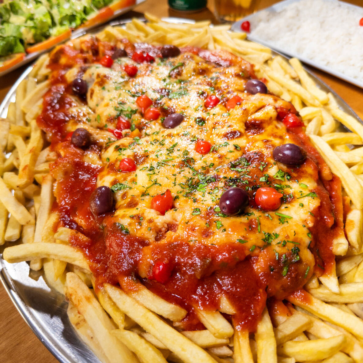 Beef de Mignon empanado servido ao Molho Vermelho Artesanal e mussarela e gratinado com parmessão. Servido com arroz branco, batatas fritas e saladas do Cheff. Serve 5 pessoas