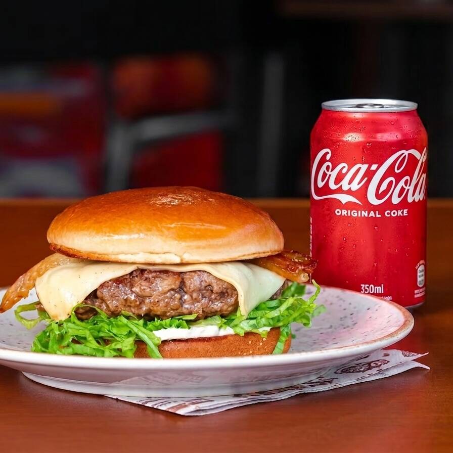Pão Brioche, blend bovino feito na casa de 180g, queijo muçarela, alface, bacon artesanal e maionese Vaca no Pão + Coca-Cola sem Açúcar 350ml