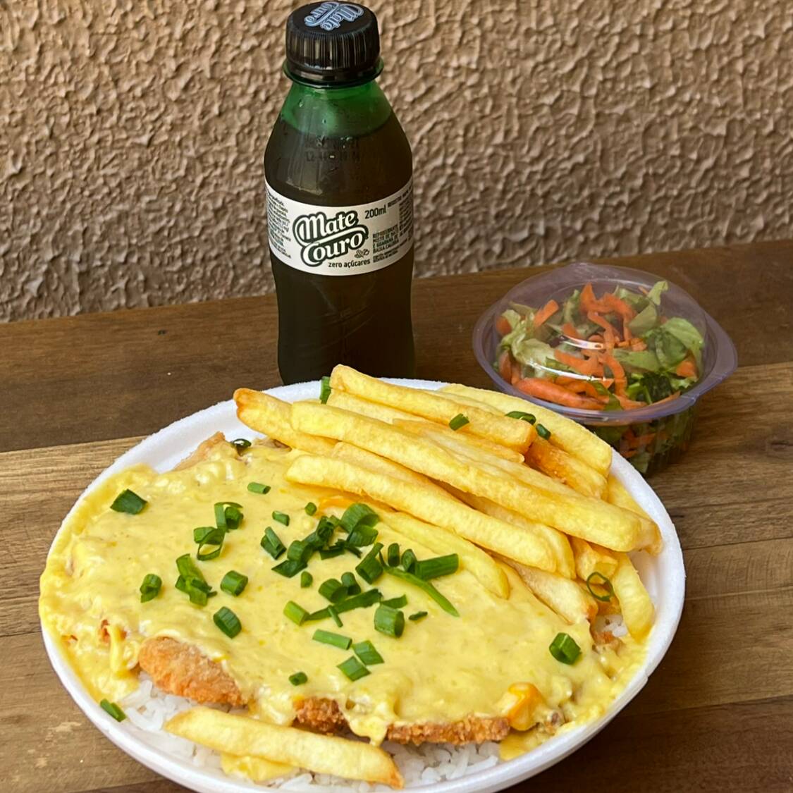 Bife á Milanesa (Empanado na Farinha Panko e Frito), ao Molho de Creme de Milho (Requeijão, Creme de Leite, Milho e Temperos da Casa). Acompanha Arroz, Batata Frita, Feijão, e Salada Separada + Refrigerante de Brinde 200ml