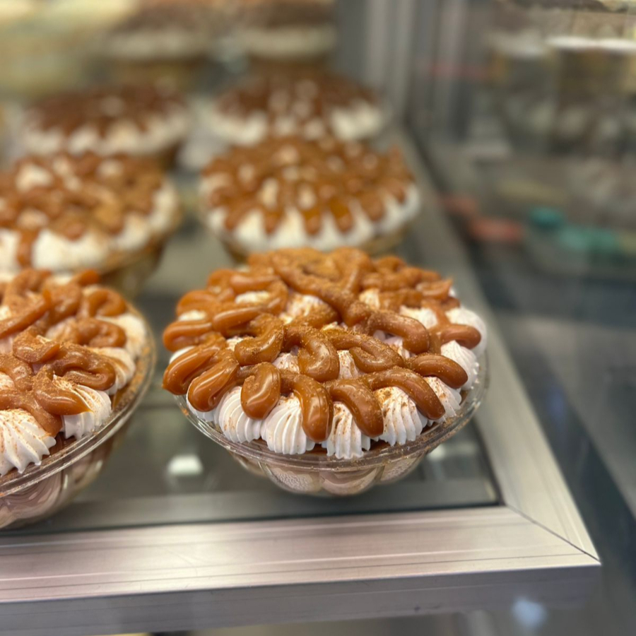 Uma torta que combina as palavras Banana e Toffee (caramelo), com camadas de biscoito triturado com manteiga, um cremoso doce de leite (toffee), fatias de banana fresca e uma cobertura generosa de chantilly, finalizada com raspas de chocolate