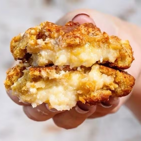 Massa de baunilha macia e crocante com um sabor suave de coco, lascas de caramelo, coco ralado, amêndoas laminadas e pedaços de chocolate nobre branco, recheado com um delicioso cremoso de coco, Uma combinação irresistível de sabores e textura.