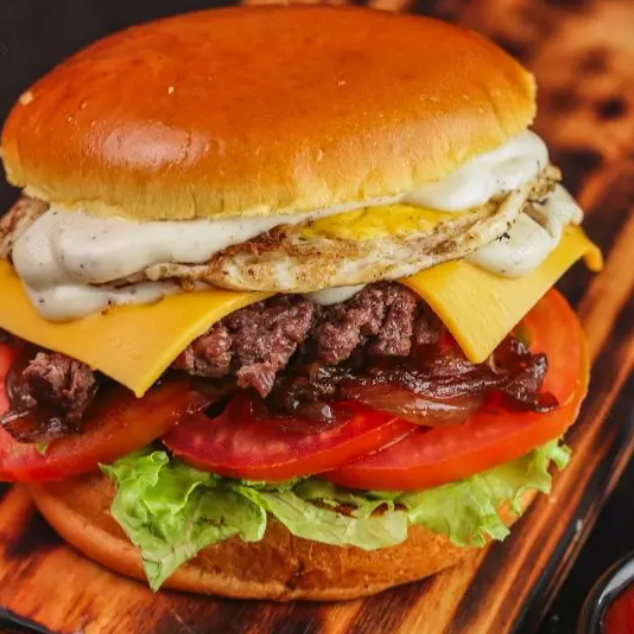 O 'Bola Barrigola Egg' da linha premium da vila é uma verdadeira explosão de sabores. O pão bola, macio e fresco, abriga uma suculenta carne 100% artesanal, cuidadosamente tostada na chapa para realçar seu sabor autêntico. O queijo cheddar, derretido na medida certa, combina perfeitamente com o ovo frito, que adiciona uma textura cremosa ao prato. A alface, o tomate e a cebola, regados ao molho shoyo, proporcionam um toque de frescor e um sabor único. Para finalizar, uma generosa camada de maionese cremosa, feita 100% artesanal, que eleva o sabor a outro nível. Uma verdadeira obra-prima culinária que agrada até os paladares mais exigentes.