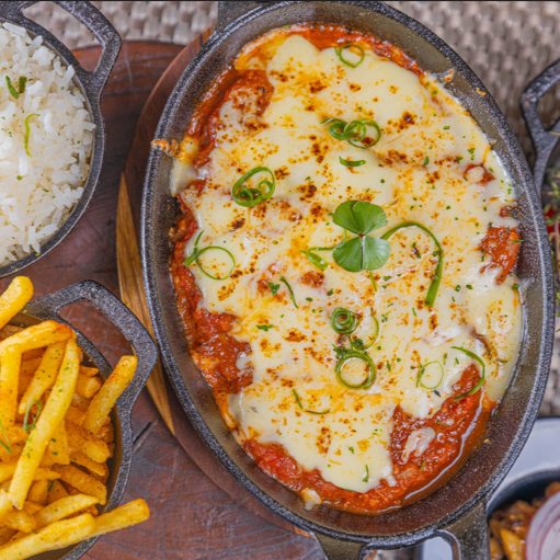 Tiras de abobrinha empanada com farinha panko, molho de tomate artesanal feito na brasa e finalizada com queijo gratinado na Parrilla. Acompanha arroz branco e fritas.