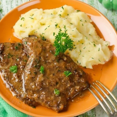 Bife frito com purê por cima acompanhado de arroz, macarrão, feijão, salada e farofa.
