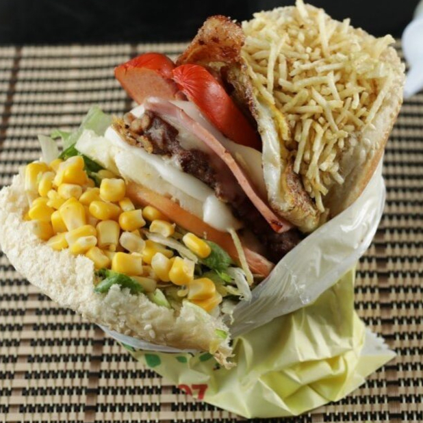 X Tudo completo e saboroso, para quem Deu Fome de verdade!
Ingredientes:
• Bacon Crocante
• 1 Burger da Casa (100g)
• Queijo Mussarela Derretida
• Salsicha
• Ovo na Chapa
• Milho
• Batata Palha Crocante
• Alface Americana
• Tomate Fatiado