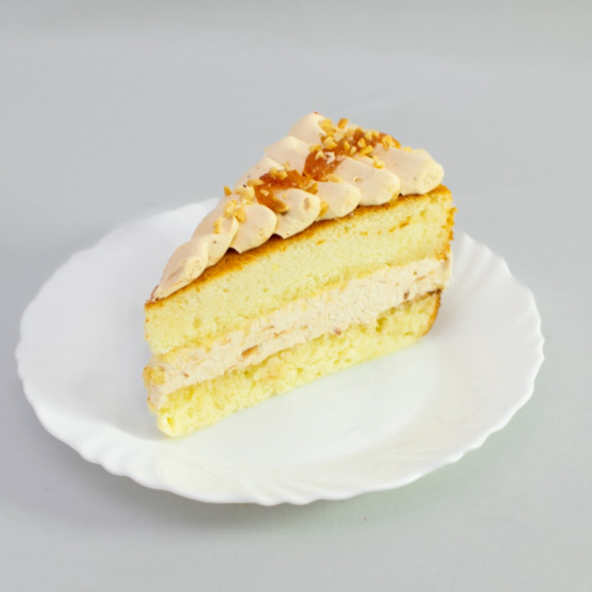 Fatia de torta de cupuaçu com doce leite e amendoim por cima .