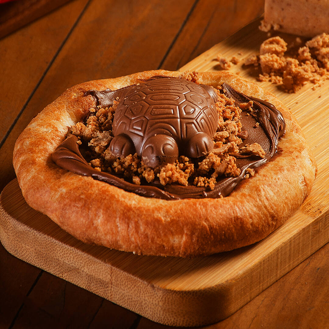 Recheada com o irresístivel sabor do chocolate ao leite, finalizada com paçoca triturada e, no topo,  uma tortuguita de chocolate.